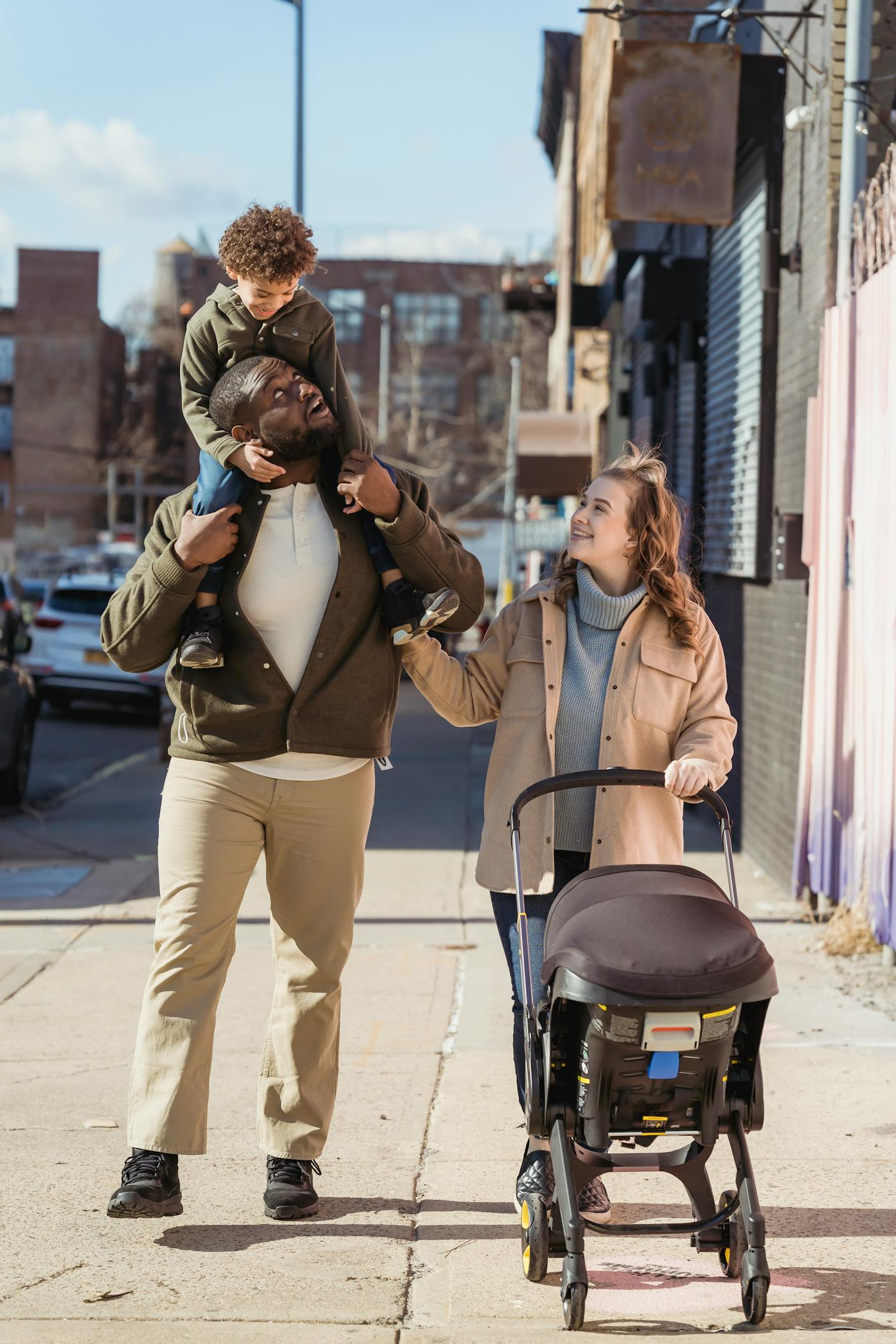 A diverse young family walking together down a sunny street