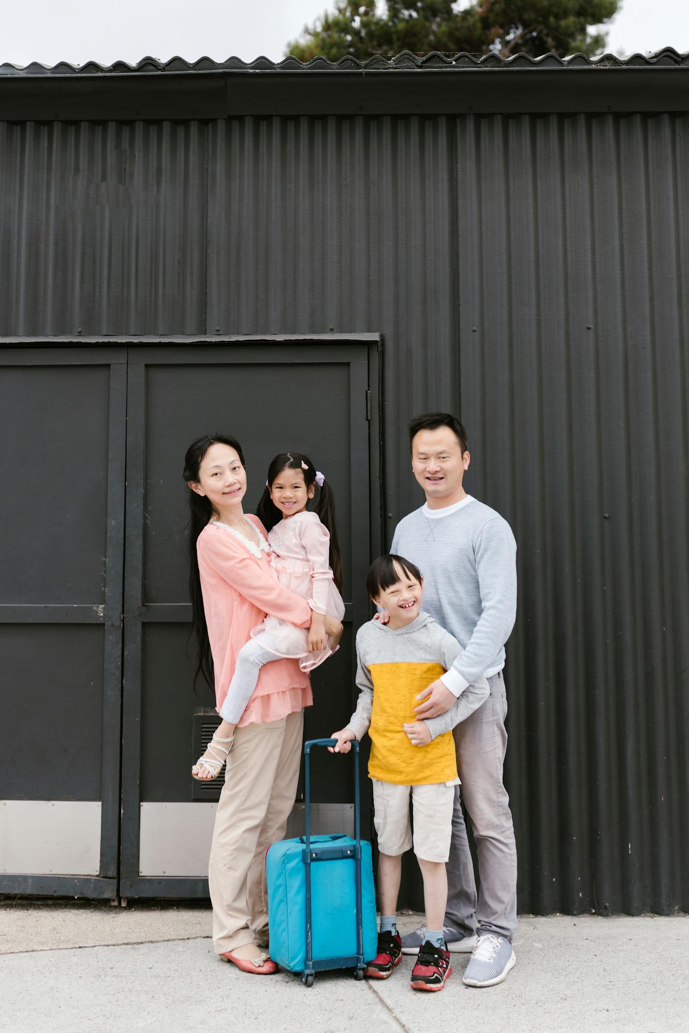 A smiling family of four, including a child with Down syndrome, standing together